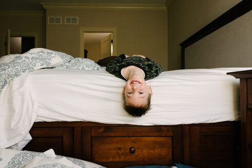 Porträt eines glücklichen Jungen, der zu Hause auf dem Bett liegt - CAVF14553