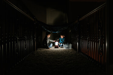 Brothers playing with lantern in darkroom at home - CAVF14554