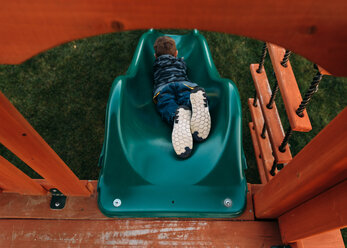 High angle view of playful boy sliding at park - CAVF14564