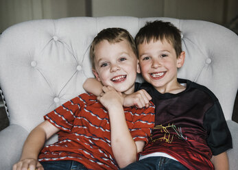 Portrait of cheerful brothers sitting on chair - CAVF14575