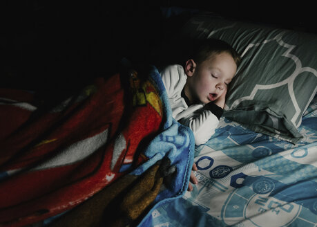 High angle view of boy sleeping on bed in darkroom at home - CAVF14590