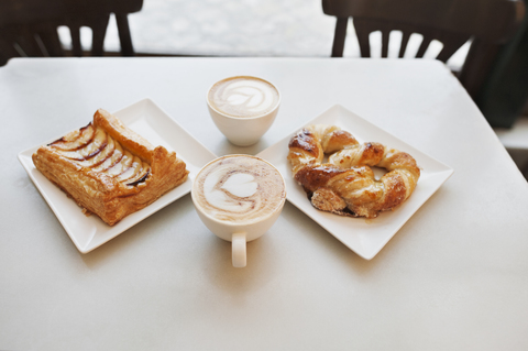 Hohe Winkel Ansicht von Cappuccino und Gebäck auf dem Tisch im Café, lizenzfreies Stockfoto