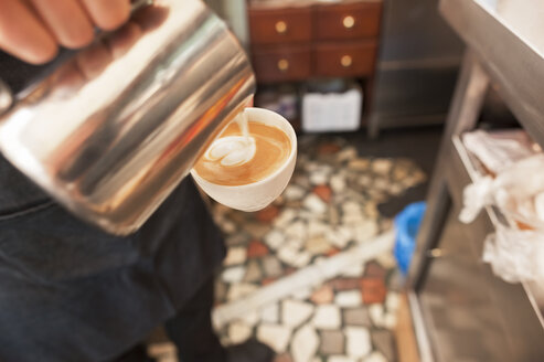 Ausgeschnittenes Bild eines Mannes, der auf einer Kaffeetasse Schaum macht - CAVF14657