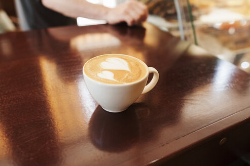 Hohe Winkel Ansicht von Cappuccino auf Holztisch in Café - CAVF14658