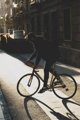 Mann fährt bei Sonnenuntergang mit dem Fahrrad auf dem Fußweg - CAVF14682