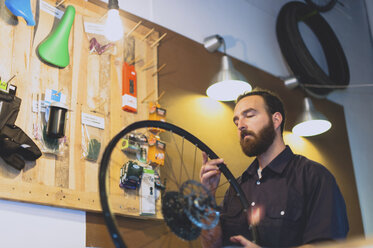 Mechaniker betrachtet einen Fahrradreifen in der Werkstatt - CAVF14684