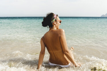 Woman lying on the beach without the bikini top looking at camera stock  photo - OFFSET