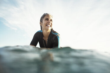 Oberflächenniveau einer glücklichen, nassen Frau beim Surfen auf dem Meer gegen den Himmel - CAVF14741