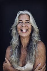 Portrait of cheerful mature woman with long gray hair against blue background - CAVF14763