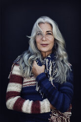 Thoughtful mature woman wearing sweater against blue background - CAVF14767