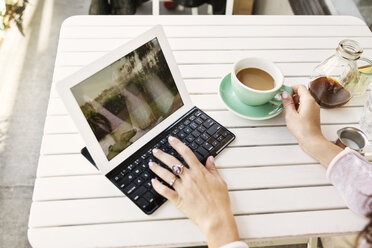 Cropped image of woman using tablet computer at sidewalk cafe - CAVF14804