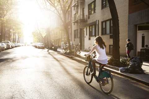 Rear view of young woman riding bicycle on street stock photo