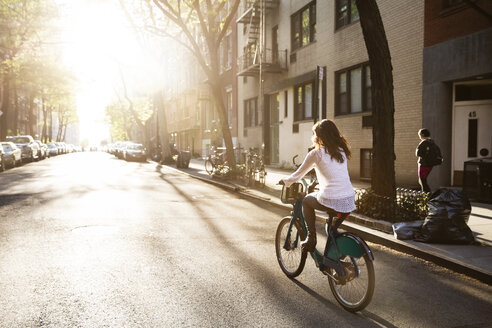 Rückansicht einer jungen Frau beim Fahrradfahren auf der Straße - CAVF14827
