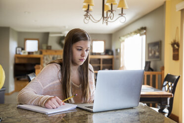 Mädchen schaut auf Laptop auf Tisch zu Hause - CAVF14928