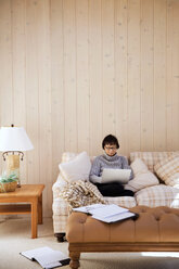 Ältere Frau benutzt Laptop im Wohnzimmer zu Hause - CAVF14967