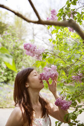 Beautiful woman smelling flowers in park - CAVF15026