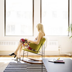 Side view of businesswoman sitting on armchair in creative office - CAVF15081