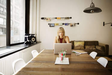 Businesswoman using laptop in creative office - CAVF15089