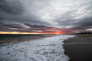 Sea waves rushing at shore against cloudy sky during sunset - CAVF15108