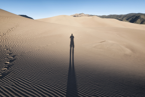 Schatten einer Person auf Sand, lizenzfreies Stockfoto