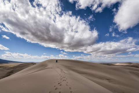 Distant view of people leaving behind footprints in desert stock photo