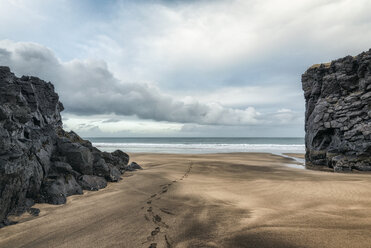 Shoe prints at sandy beach against cloudy sky - CAVF15163