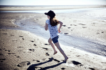 Playful girl running at beach on sunny day - CAVF15196