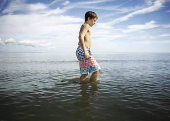 Seitenansicht eines Jungen ohne Hemd, der im Meer gegen den Himmel läuft - CAVF15204