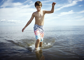 Shirtless boy walking in sea against sky - CAVF15205