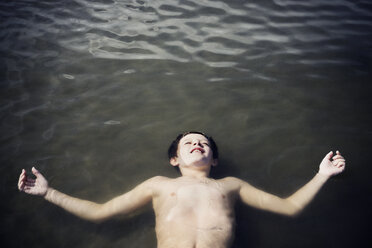 Draufsicht auf einen auf dem Meer treibenden Jungen ohne Hemd an einem sonnigen Tag - CAVF15209