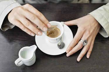 Draufsicht auf eine Frau, die Kaffeepulver in eine Tasse gießt - CAVF15223