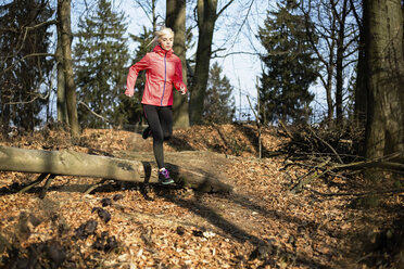 Entschlossene sportliche Frau beim Laufen im Wald - CAVF15226