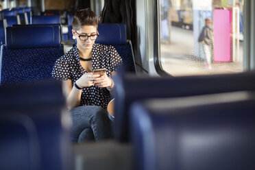 Junge Frau benutzt Smartphone im Zug - CAVF15231