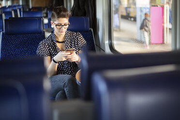 Young woman using smart phone in train - CAVF15231