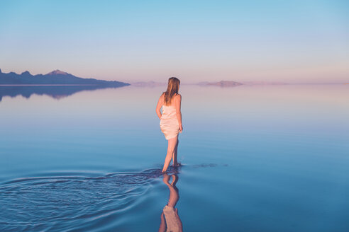 Rückansicht einer Frau, die im See der Bonneville Salt Flats gegen den klaren Himmel läuft - CAVF15239
