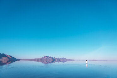 Entfernte Ansicht einer Frau in den Bonneville Salt Flats vor blauem Himmel - CAVF15241