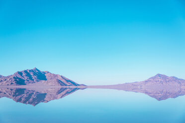 Blick auf die Berge, die sich im See der Bonneville Salt Flats vor blauem Himmel spiegeln - CAVF15243