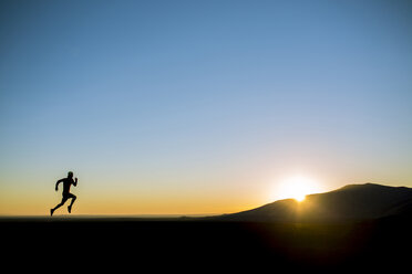 Silhouette Mann läuft auf Feld gegen klaren blauen Himmel - CAVF15244