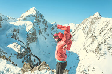 Seitenansicht einer Frau mit Jacke, die vor einem schneebedeckten Berg steht - CAVF15268