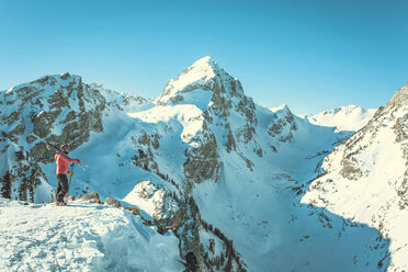 Side view of female skier standing against snowcapped mountains - CAVF15270