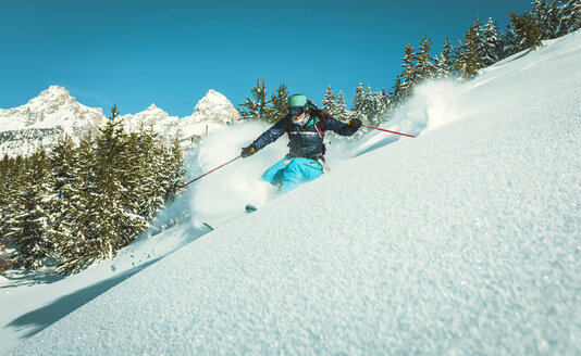Frau beim Skifahren auf der Skipiste vor blauem Himmel - CAVF15274