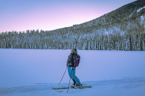 Müde Skifahrerin auf verschneitem Feld vor Bäumen stehend - CAVF15278