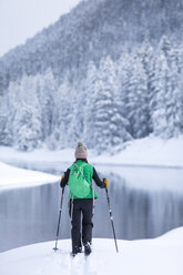 Rückansicht einer Wanderin, die am schneebedeckten Seeufer steht - CAVF15283