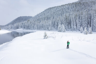 Hohe Winkelansicht einer Wanderin, die auf einem schneebedeckten Feld steht und fotografiert - CAVF15284