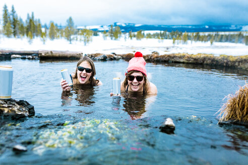 Portrait of happy friends with drink cans enjoying in lake - CAVF15288