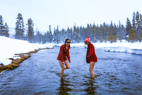 Female friends enjoying in lake against sky during winter - CAVF15289