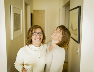 Fröhliche Schwestern, die zu Hause im Korridor stehen - CAVF15298