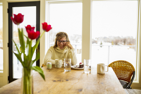 Porträt einer Frau, die zu Hause am Tisch sitzt, lizenzfreies Stockfoto