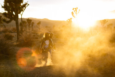 Volle Länge der spielerischen Frau, die Sand auf einem Feld im Joshua Tree National Park tritt - CAVF15320