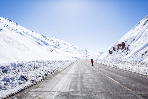 Mid distance view of hiker skating on road by snow covered mountains at Joshua Tree National Park - CAVF15325